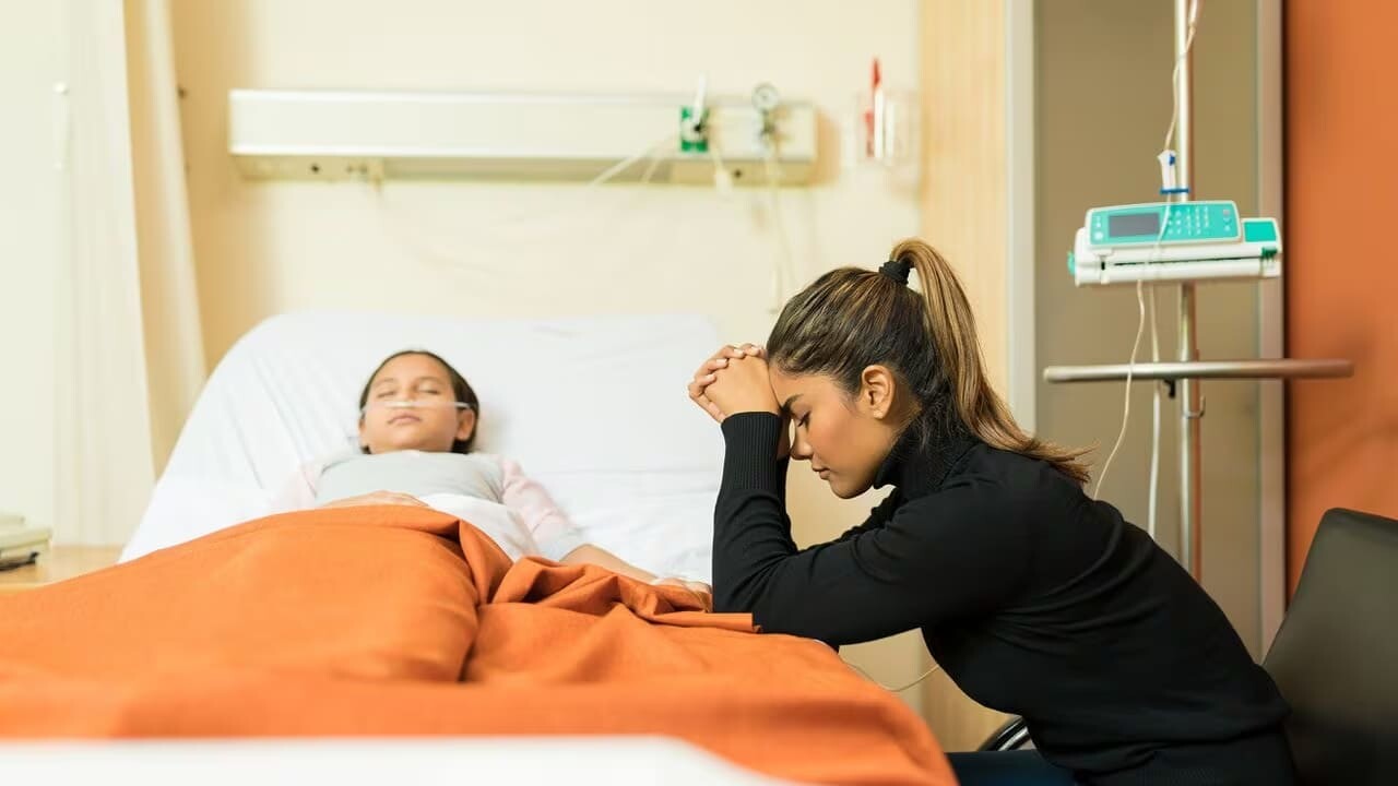 a woman sitting in a hospital bed with her head in her hands